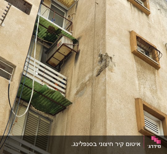 מרפסת עם גגון ירוק ומזגן ישן על קיר בניין